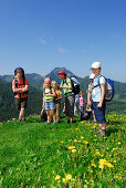 Wandergruppe mit Kindern auf einer Blumenwiese, Bayerische Alpen, Oberbayern, Bayern, Deutschland