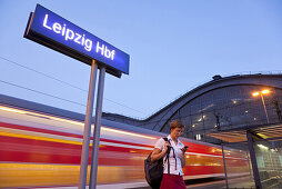 Frau mit einem Handy steht auf einem Bahnsteig, Leipzig, Sachsen, Deutschland