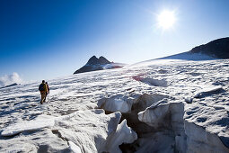 Zwei Männer wandern entlang von Gletscherspalten auf dem Hüfifirn, Clariden im Hintergrund, Kanton Uri, Schweiz