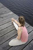 Young woman stretching on a jetty at lake Starnberg, Bavaria, Germany