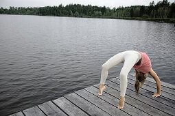 Young woman bridging on a jetty at lake Starnberg, Bavaria, Germany