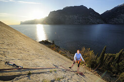 Woman climbing at ledge Corno di Bo, lake Garda in background, Nago-Torbole, Trentino-Alto Adige/South Tyrol, Italy