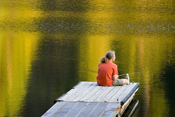Fisherman in red shirt trying his luck from a dock on Black Pine Lake North Cascades Washington USA