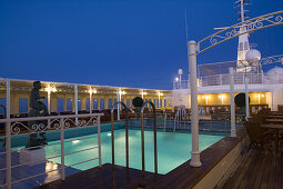 Beleuchteter Pool an Deck von Kreuzfahrtschiff MS Deutschland am Abend, Atlantischer Ozean