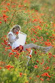 Young woman sitting on a chair in the middle of a poppy field