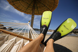 Womans' legs with flippers lying on a hammock under a thatched sun shade, Mallorca, Balearic Islands, Spain