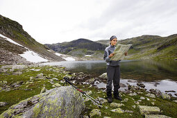 Junge Frau liest Wanderkarte in karger Landschaft auf dem Rimstigen, Naerofjord, Sogn og Fjordane, Norwegen, Skandinavien, Europa