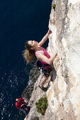 Eine junge Frau, und ein junger Mann klettern an den Klippen der Bucht von Zurrieq, Malta, Europa