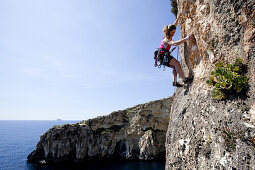 Eine junge Frau klettert an den Klippen der Bucht von Zurrieq, Malta, Europa