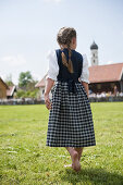 Barfoot girl wearing dirndl walking over meadow, May Running, Antdorf, Upper Bavaria, Germany
