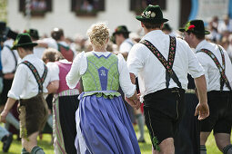 Paare in Tracht laufen über Wiese, Mailaufen, Antdorf, Oberbayern, Deutschland