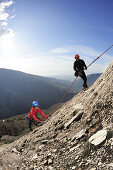 Woman climbing at Gneiss rock face, man abseiling, rappelling, Massa, Tuscany, Italy