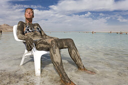 Woman smeared with mineral mud sunbathing, Dead Sea, En Bokek, Israel, Middle East