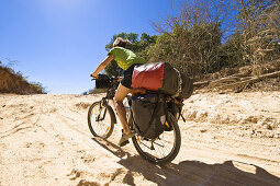 Woman cycling with a mountainbike on sandy track, Madagaskar