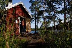 Woman and small cottage at the lake Tärnättvatten, nationalpark Skuleskogen, Höga Kusten, Västernorrland, Sweden, Europe