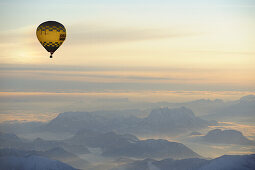 Luftaufnahme von Heißluftballon über Kaisergebirge bei Sonnenaufgang, Berchtesgadener Alpen im Hintergrund, Tirol, Österreich, Europa
