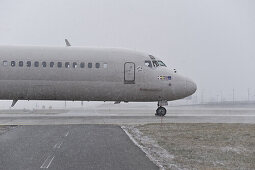 Airliner passing airport taxiway in snowfall, Munich airport, Bavaria, Germany