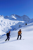 Two women backcountry skiing, ascending mountain towards Hohe Warte, Olperer in background, Hohe Warte, Schmirntal valley, Tuxer Alpen range, Tyrol, Austria
