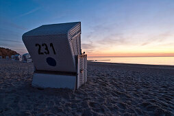 Roofed wicker beach chairs in sunset, Sylt island, Schleswig-Holstein, Germany