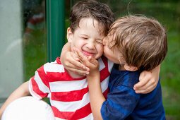 Junge (6 - 7 Jahre) küsst Freund auf die Wange