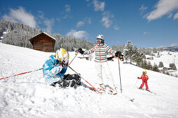 Familie auf Skipiste, Junge sitzt im Schnee, Schlößlelift, Kleinwalsertal, Vorarlberg, Österreich