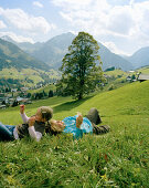 Two children rolling down the grass, Mountain meadows,Hirschegg, Kleinwalsertal, Austria