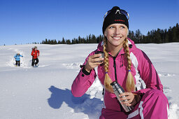 People snowshoeing, young woman having a rest, Hemmersuppenalm, Reit im Winkl, Chiemgau, Upper Bavaria, Bavaria, Germany, Europe