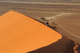Personen gehen auf roter Sanddüne im Sossusvlei, Düne 45, Sossusvlei, Namib Naukluft National Park, Namibwüste, Namib, Namibia