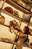 Junge Frau wählt eine Handtasche, Adolfo Dominguez Designer Geschäft, Provinz Valencia, Valencia, Spanien