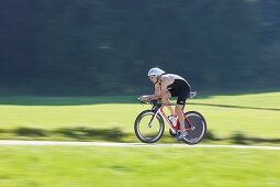 Male racing cyclist with disc wheel on road near Munsing, Upper Bavaria, Germany