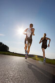 Two runners on road near Munsing, Upper Bavaria, Germany