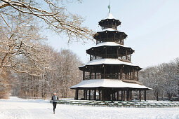Jogger near snow-covered Chinese Tower, English Garden, Munich, Bavaria, Germany