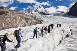 People hiking on grenz glacier to Monte Rosa hut, Liskamm in background, Zermatt, Canton of Valais, Switzerland, myclimate audio trail