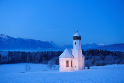 Verschneite Kirche vor Zugspitze und Ammergauer Alpen am Abend, Penzberg, Werdenfelser Land, Oberbayern, Bayern, Deutschland, Europa