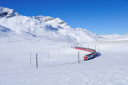 Zug der Rhätische Bahn fährt durch Winterlandschaft zum Berninapass, UNESCO Weltkulturerbe Rhätische Bahn, Rhätische Bahn, Albula-Bernina-Linie, Berninabahn, Berninagruppe, Oberengadin, Engadin, Graubünden, Schweiz, Europa