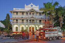 People in front of the old pharmacy at dusk, Mizingani Road, Stonetown, Zanzibar City, Zanzibar, Tanzania, Africa