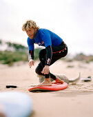 Surflehrer auf Board am Strand, Playa de Somo, bei Santander, Kantabrien, Spanien