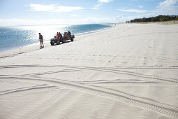 Quad bike with tourists and luggage on long beach, southern Great Keppel Island, Great Barrier Reef Marine Park, UNESCO World Heritage Site, Queensland, Australia