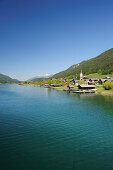 Lake Weissensee with Gatschach village under blue sky, lake Weissensee, Carinthia, Austria, Europe