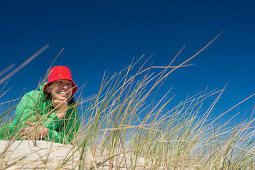 Woman lying on dune, Sylt, Schleswig-Holstein, Germany