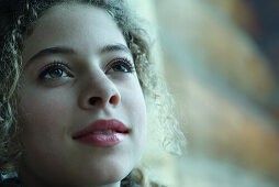 Teenage girl smiling, looking up, portrait