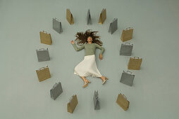 Woman lying on the ground, surrounded by shopping bags, overhead view