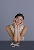 Woman sitting with toy airplane, chin resting in hands, looking up