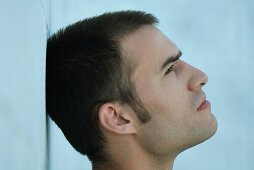 Man leaning head against wall, looking up, profile