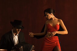 Couple tango dancing, man playing accordion in foreground