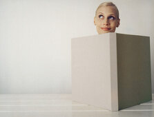 Woman behind open book, looking up, close-up