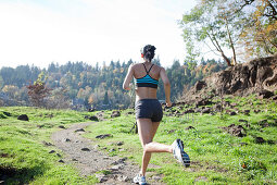 Young Woman Jogging Along Trail, Rear View