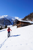 Frau auf Skitour geht auf Almgebäude zu, Marchkinkele im Hintergrund, Marchkinkele, Villgratener Berge, Hohe Tauern, Osttirol, Österreich