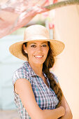 Young smiling woman, arms crossed, straw hat