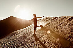 Woman Running Down Desert Sand Dune, California, USA